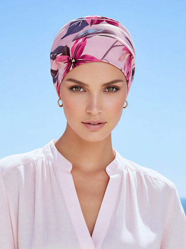 A woman wearing a pink lilac tropical floral chemo cloche cap